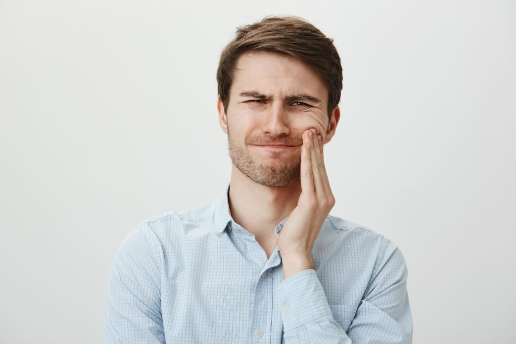 Hombre con dolor por caries en los dientes