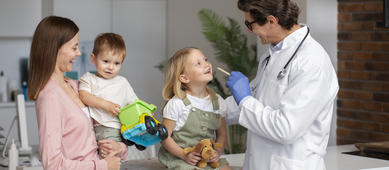 Nuestros Servicios Banner de servicio de Pediatría: Médico revisando la garganta de una niña con su madre y su hermano bebé.